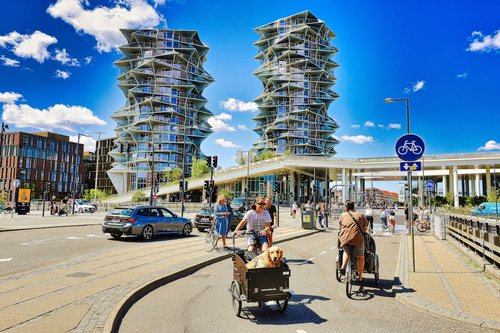 People cycling past modern buildings on a sunny day