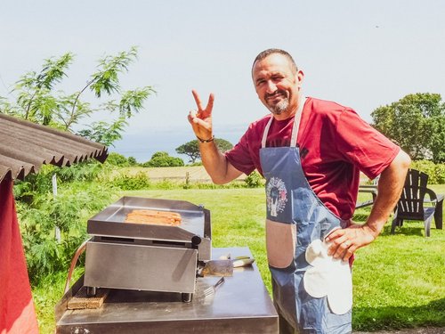 Man grilling hot dogs and giving peace sign