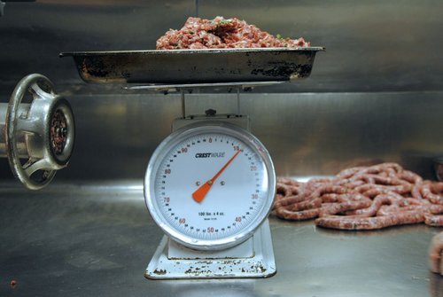 Ground meat on a scale next to sausages